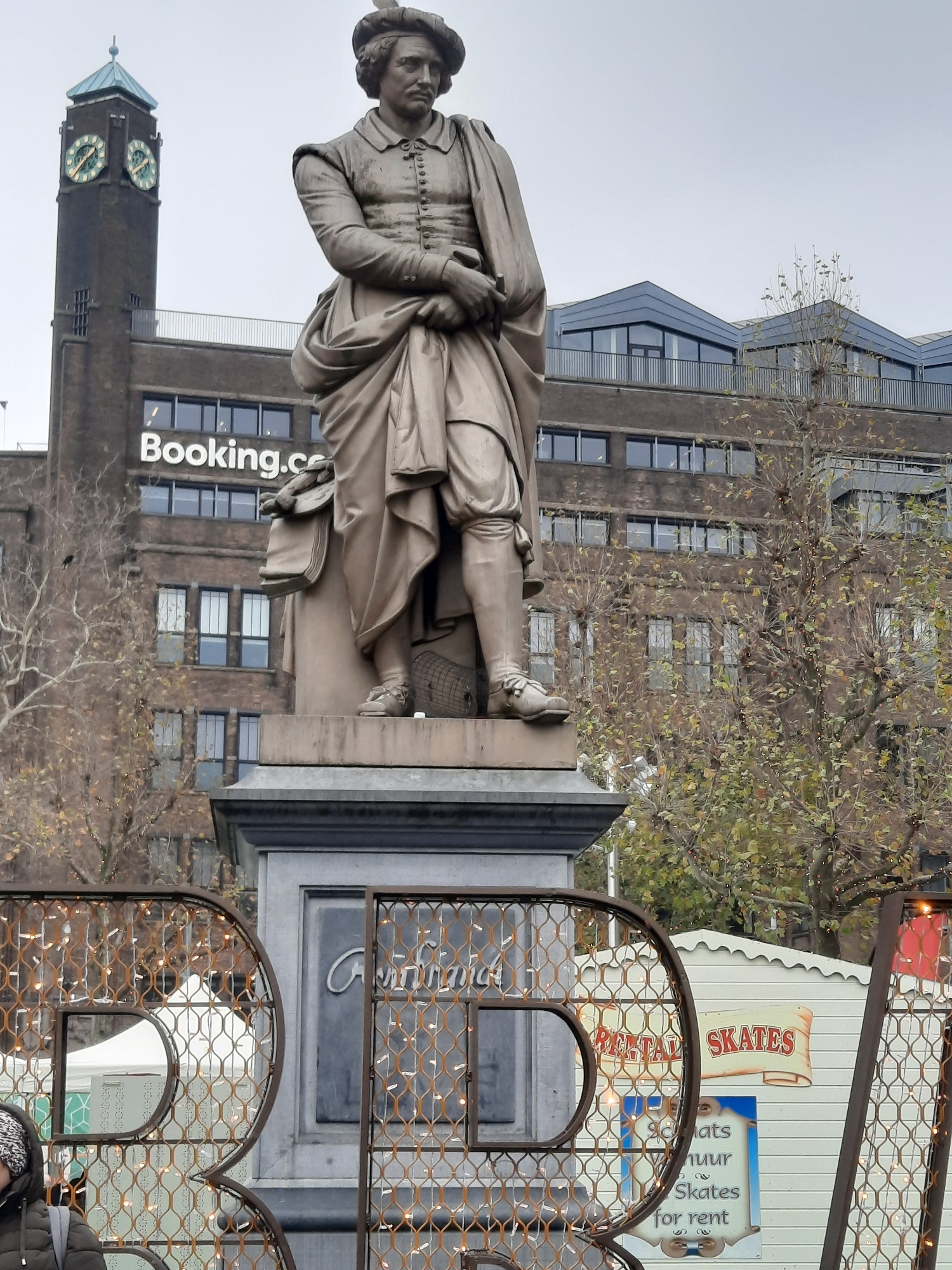 Rembradt tér a művész szobrával, háttérben a booking.com szállásfoglaló portál épületével.