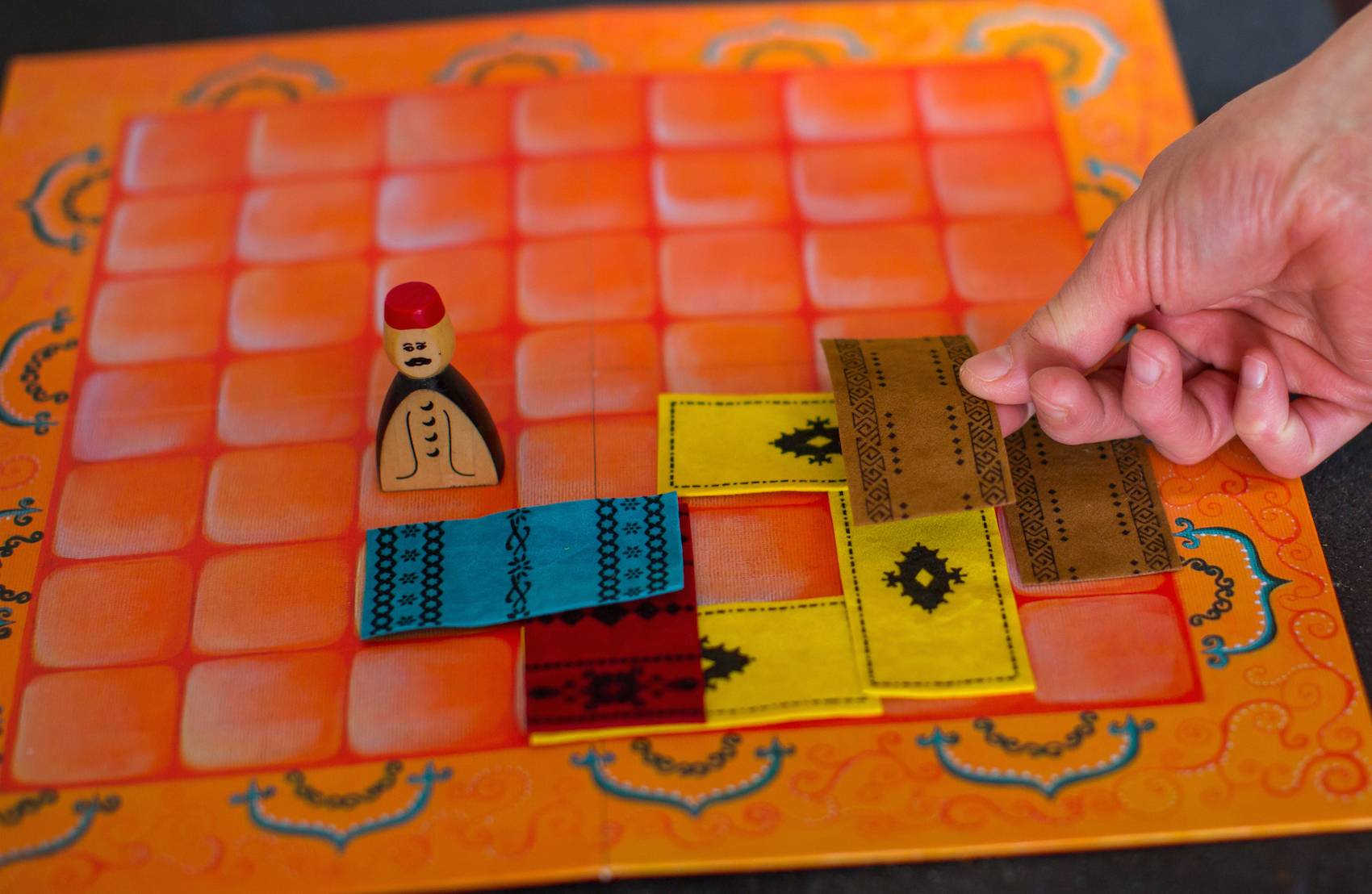 A barna szőnyeget fektető játékos két sárga szőnyegfelet takar le.