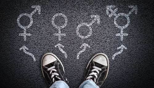 a-person-standing-on-asphalt-road-with-gender-symbols-of-male-female-bigender-and-transgender.jpg