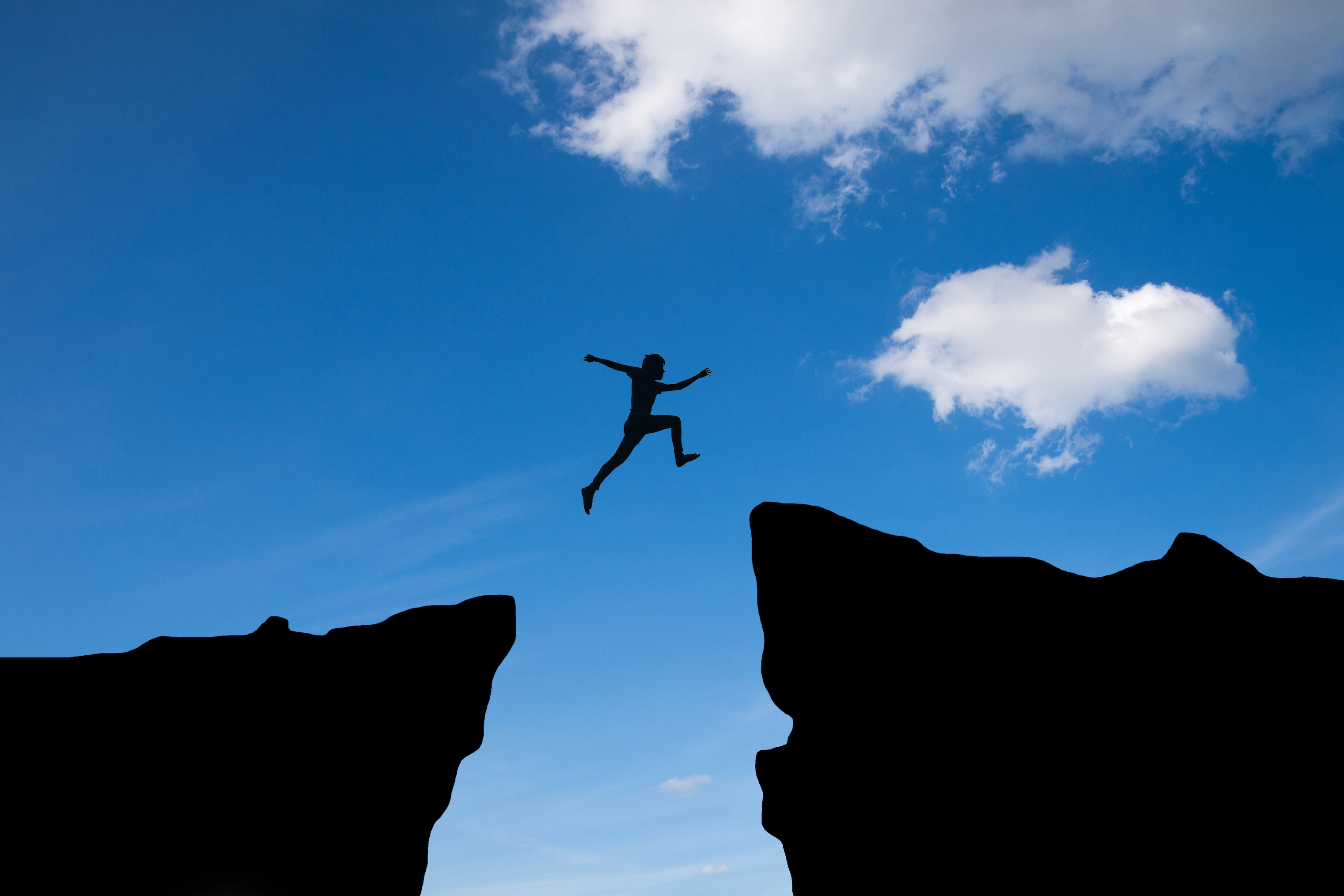 man-jump-through-gap-hill-man-jumping-cliff-blue-sky-business-concept-idea.jpg