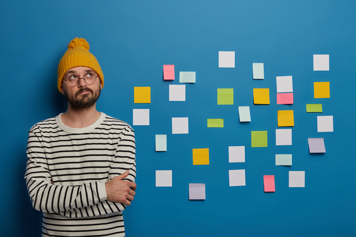 thoughtful-man-spectacles-yellow-headwear-striped-jumper-has-creative-occupation-focused-stands-with-hands-crossed.jpg