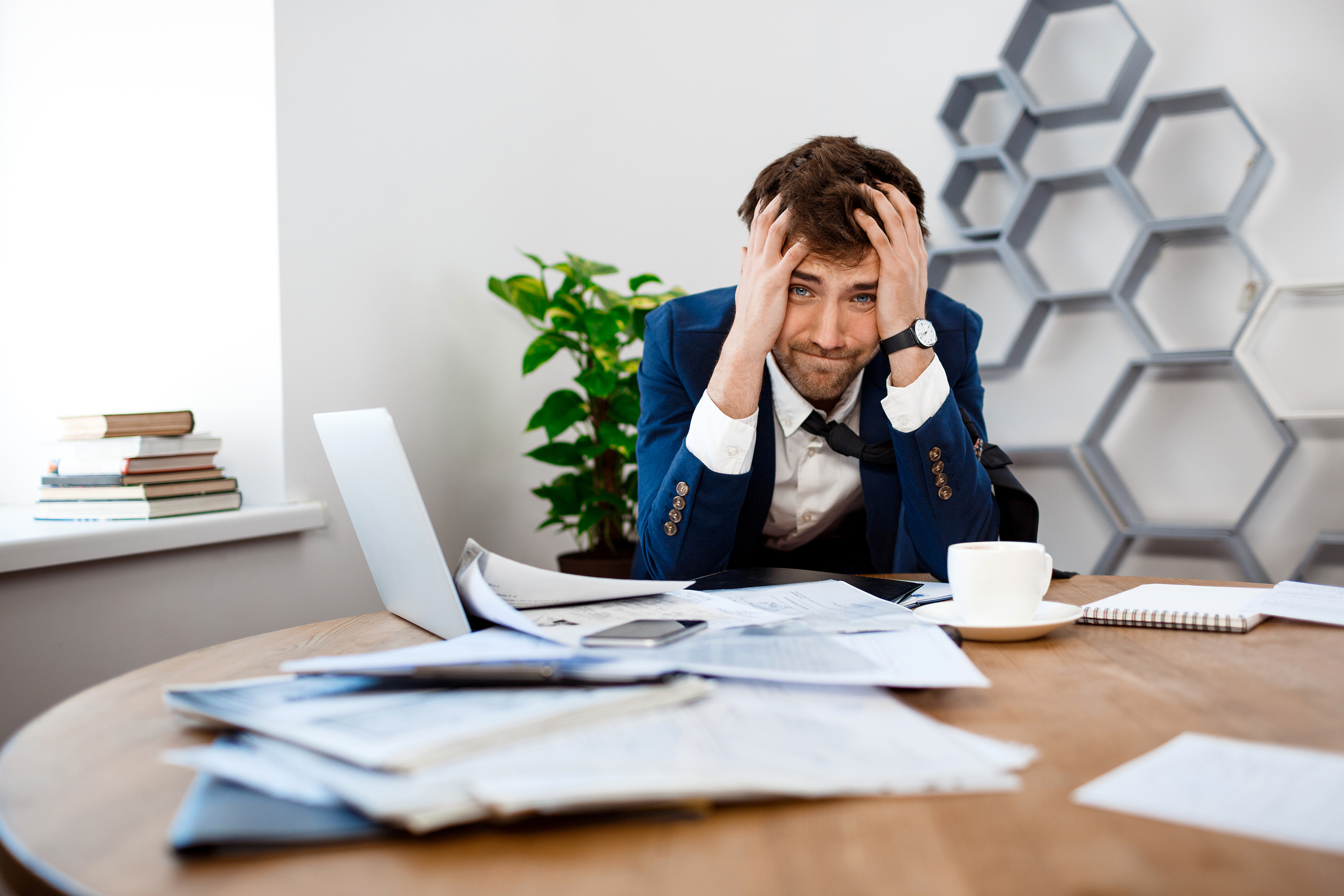 upset-young-businessman-sitting-workplace-office-background.jpg
