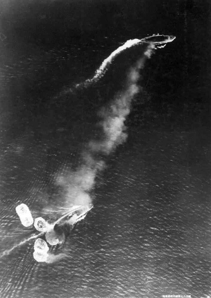 Az első bombatámadás. A képen felül a Prince of Wales, alul a Repulse. A Repulse tatja körül a becsapódó bombák vízoszlopai láthatók, a fekete füst a hajó közepét ért találatból származik.