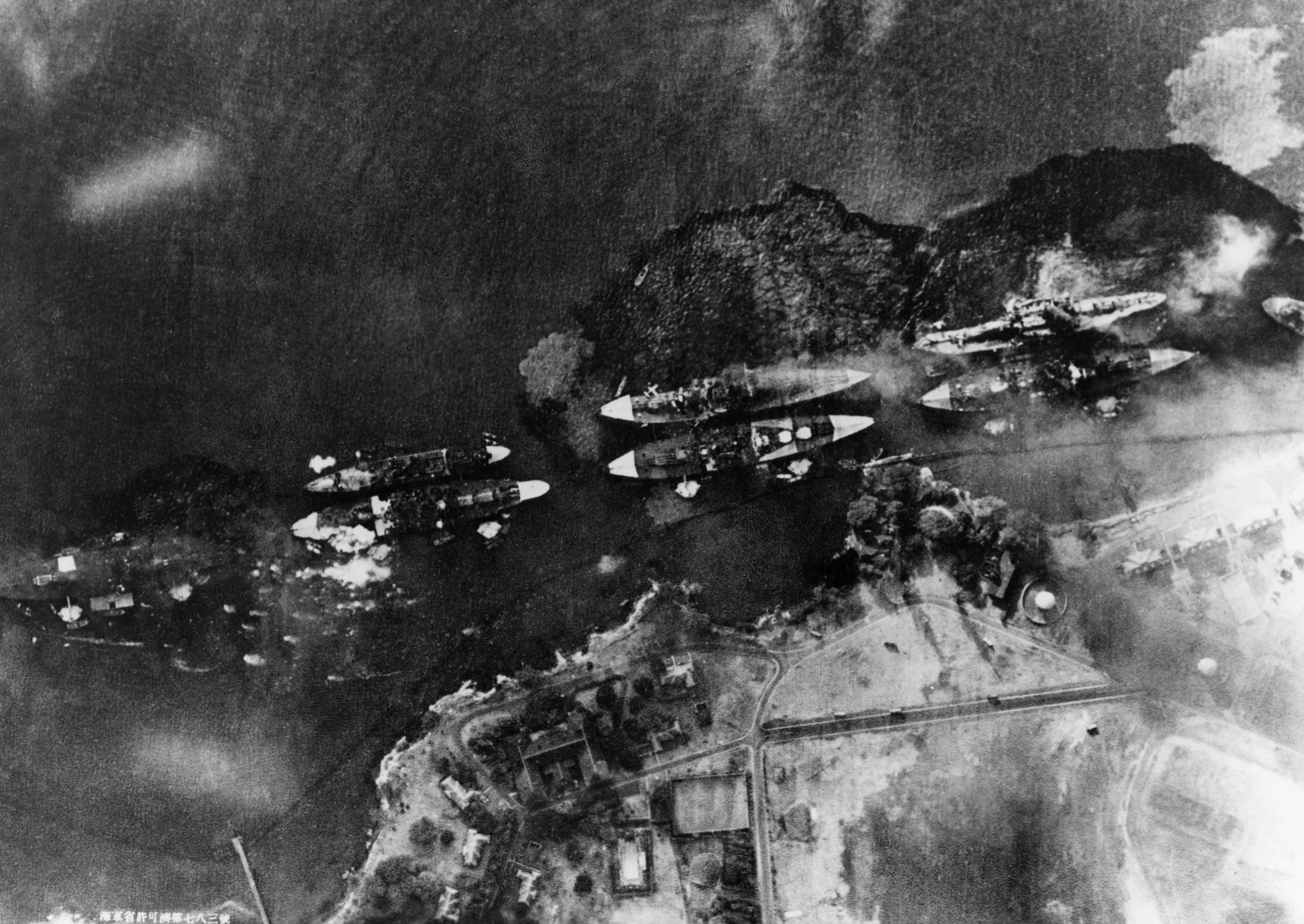 Egy japán bombázóról készült légifelvétel a támadás alatt álló csatahajókról. A külső sorban álló Oklahoma és West Virginia mellett jól láthatóak az első torpedók robbanásai által keltett lökéshullámok.