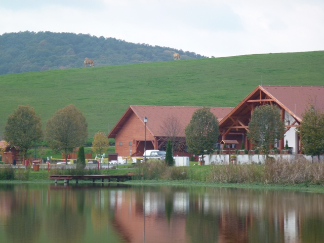 A fogadóház (csárda) és a wellness házikó a háttérben, valamint lovacskák a domboldalon