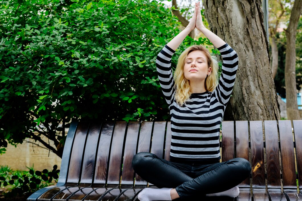 young-woman-doing-yoga-exercise-sitting-bench-park-striped-top-black-jeans_141793-6026.jpg