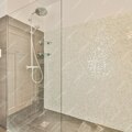"Fürdőszoba Varázslat: Üveg Zuhanyfal és Csempék Táncolása a Felújítás Kavalkádjában"