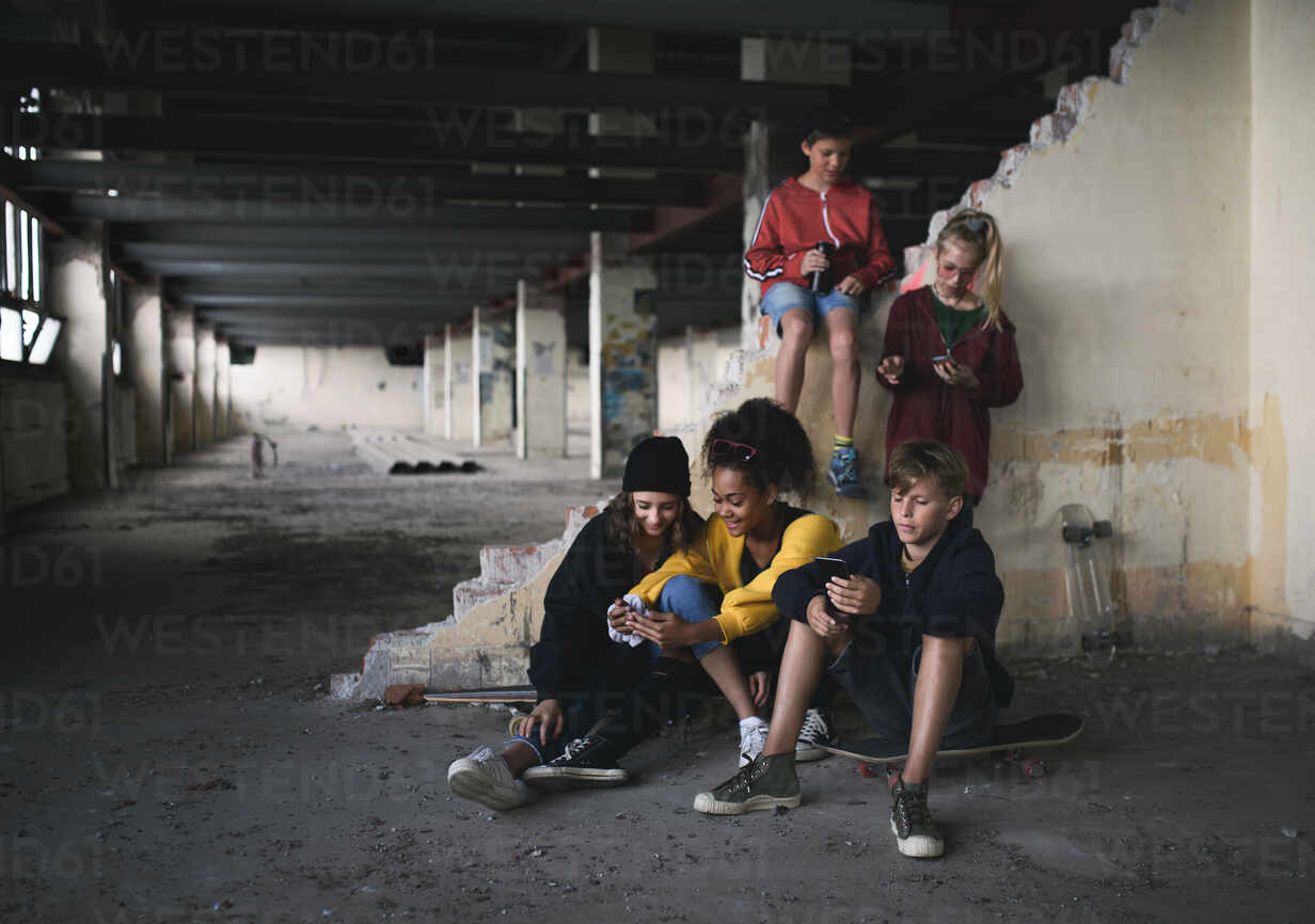 front-view-of-group-of-teenagers-gang-sitting-indoors-in-abandoned-building-using-smartphones-hpif13664.jpg