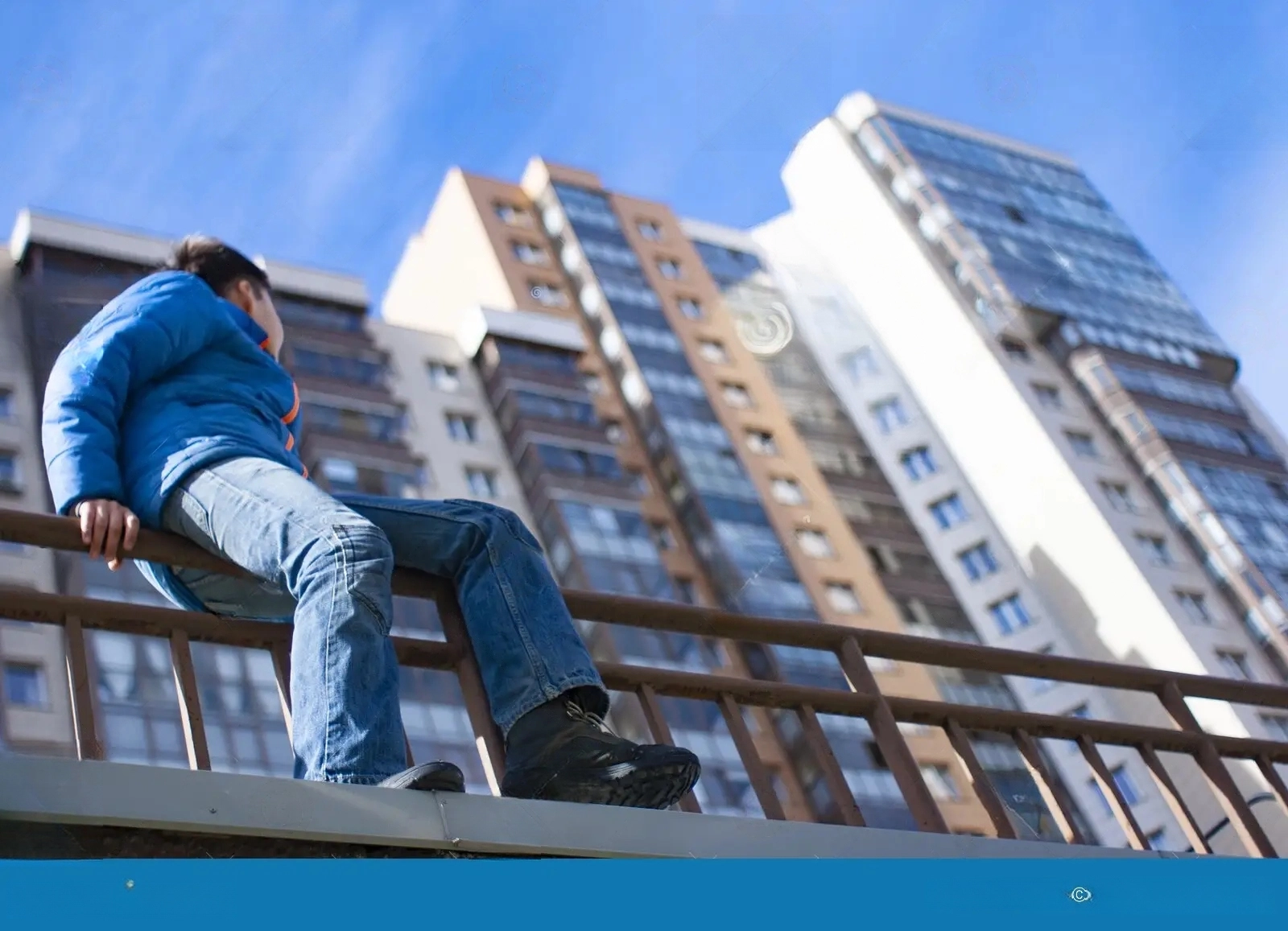 our-new-home-teenage-boy-sits-outside-railing-looks-up-high-rise-apartment-buildings-137854138-transformed.webp