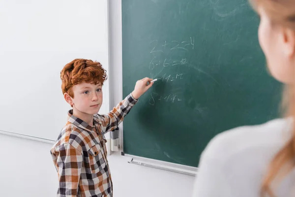 stock-photo-redhead-schoolboy-writing-chalkboard-while-looking-teacher-blurred-foreground.jpg