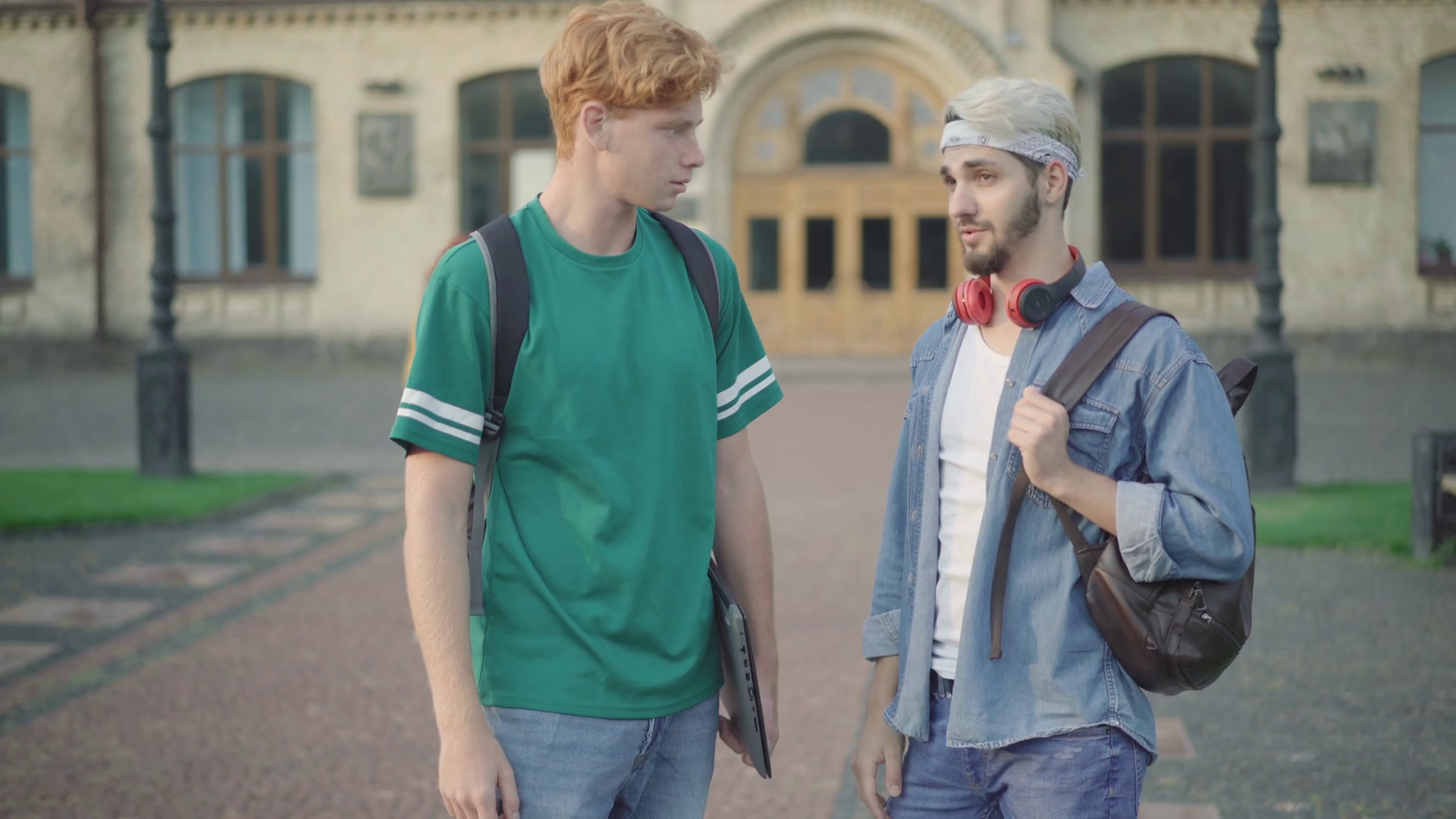 videoblocks-two-young-male-college-students-standing-on-campus-and-talking-as-beautiful-women-passing-at-the-background-portrait-of-confident-caucasian-men-chatting-after-classes-at-university_rwocftqbd_thu.png