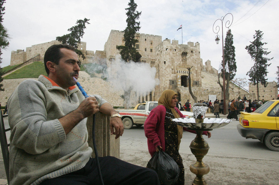 a_man_smokes_his_water_pipe_in_front_of_the_aleppo_citadel_on_march_18_2006.jpeg