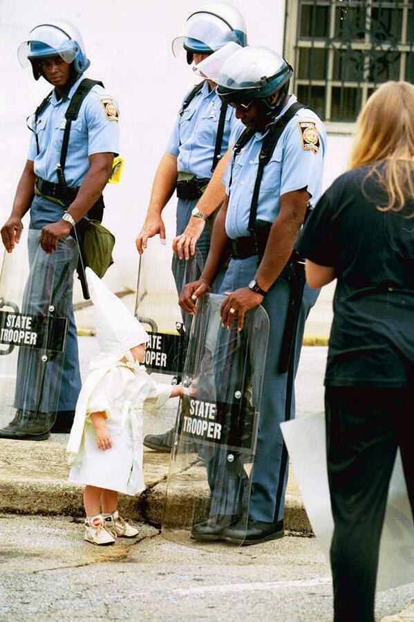 fehér kisfiú megérinti egy fekete rendőrtiszt pajzsát a ku klux klán felvonulásán.jpg