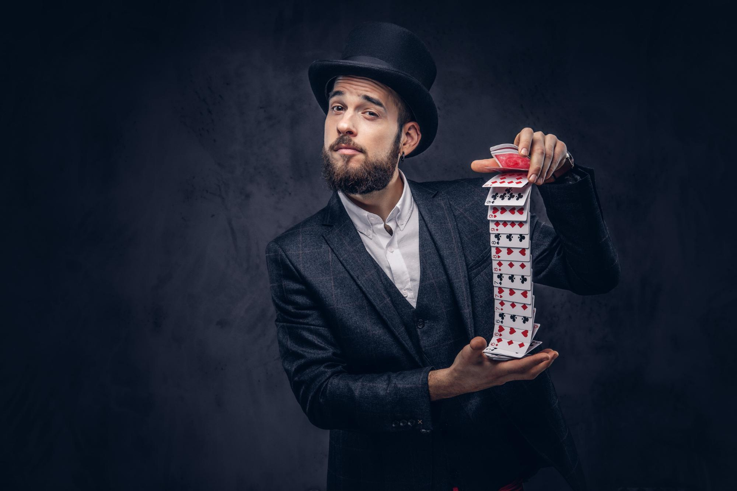 bearded-magician-black-suit-top-hat-showing-trick-with-playing-cards-dark-background_fxquadro_freepik.jpg