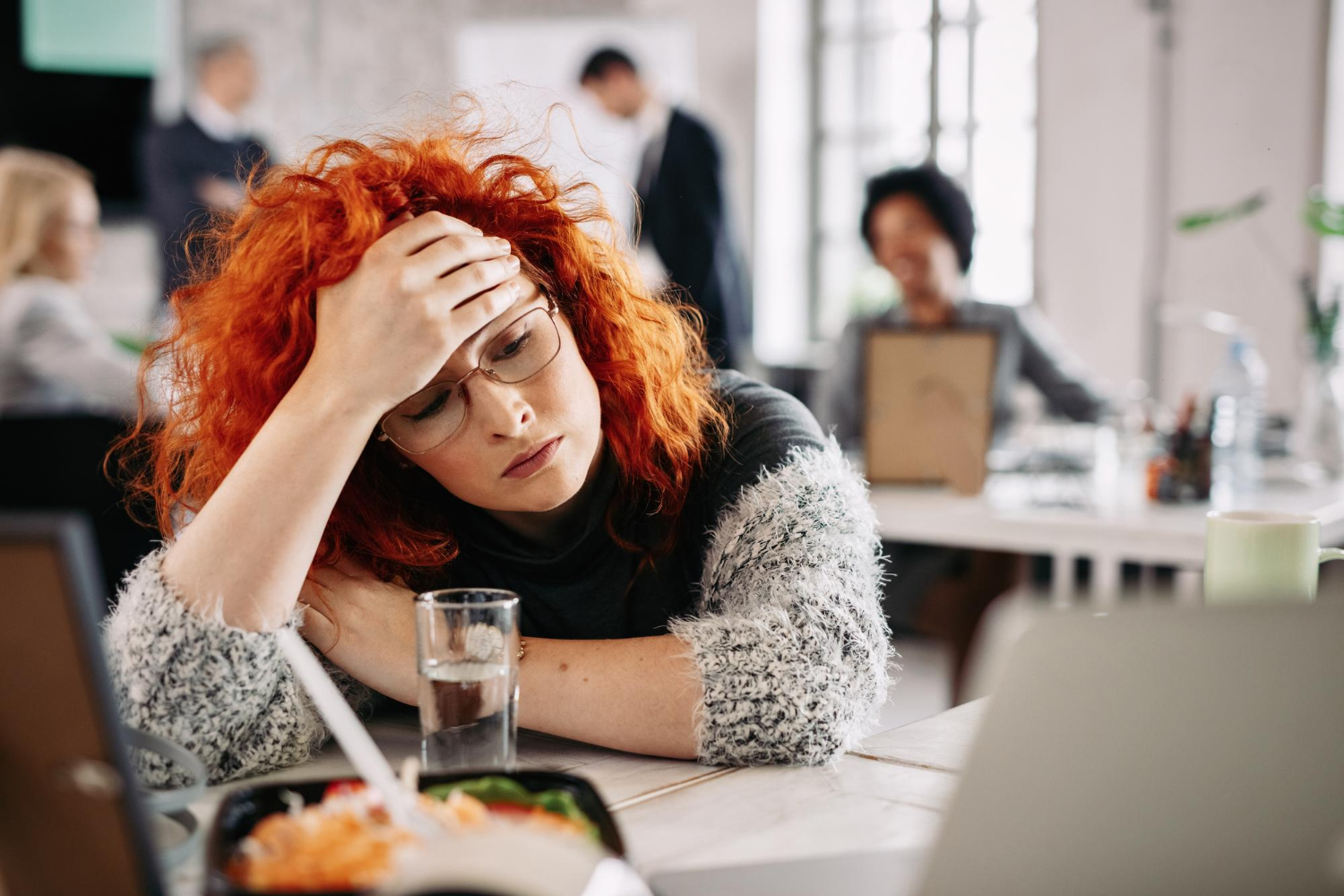 pensive-redhead-entrepreneur-feeling-tired-while-sitting-her-desk-office-there-are-people-background_drazen_zigic_freepik.jpg