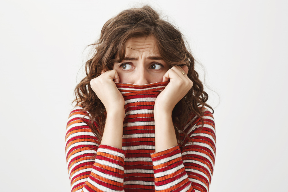 scared-timid-woman-looking-left-shivering-hiding-face-inside-sweater-collar_cookie_studio_freepik.jpg