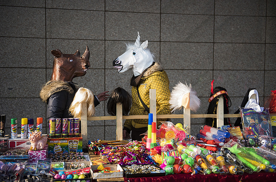 Fotó: Balázs Attila: Szilveszteri maszkokat árusító asszonyok beszélgetnek Nyíregyházán, egy bevásárlóközpont előtt, 2016<br />