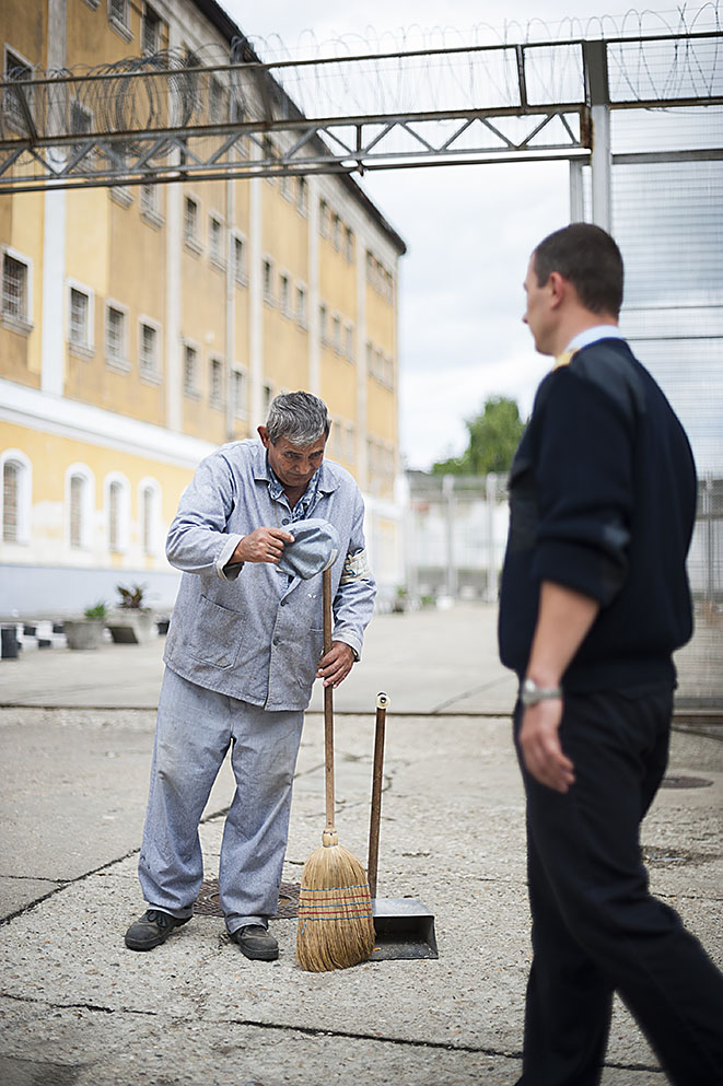 Fotó: Balázs Attila: Rontó Tihamér elítélt sapkáját levéve üdvözli a börtön egyik tisztjét a Sátoraljaújhelyi Fegyház és Börtön udvarán. Az elítéltek minden esetben így köszöntik a börtön dolgozóit, 2011<br />
