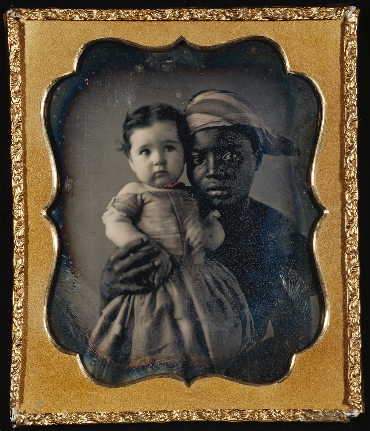 Fotó: Unknown maker (American)<br />Portrait of a Nurse and a Child<br />c. 1850<br />Daguerreotype, hand-colored<br />1/6 plate<br />Image: 6.2 x 4.8 cm (2 7/16 x 1 7/8 in.)<br />Mat: 8.3 x 7.1 cm (3 1/4 x 2 13/16 in.)<br />The J. Paul Getty Museum, Los Angeles