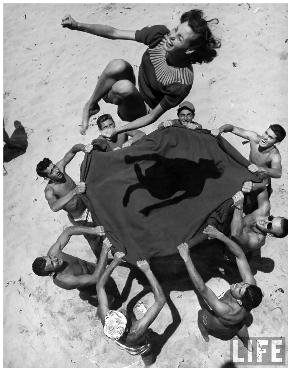 teenaged-boys-using-blanket-to-toss-their-friend-norma-baker-into-the-air-on-the-beach-1948-john-florea.jpeg