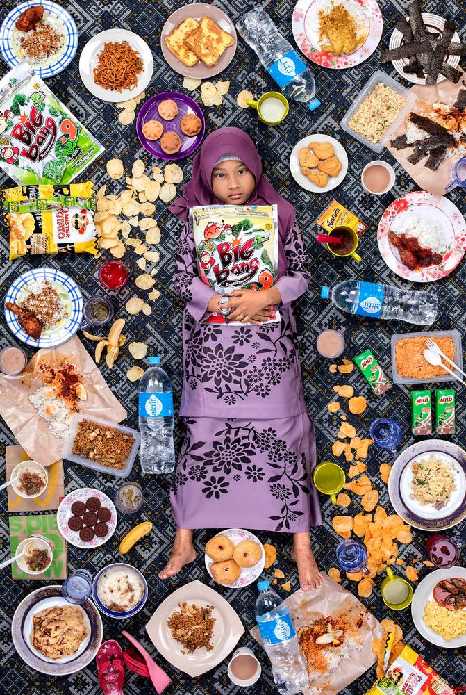 Fotó: Részlet a Daily Bread sorozatból © Gregg Segal<br /><br />Nur Zahra Alya Nabila Binti Mustakim, 7 éves, Kajang, Malajzia, 2017. március 24. <br />Nur étkezésének 90%-a házi; imádja édesanyja főztjét, különösen a nasa ayam-ot (csirke és rizs), valamint a nasi lemakját. A legegészségtelenebb étel, amelyet Nur eszik, azok a harapnivalók és édes italok, amelyeket az iskola menzájában vásárol. 