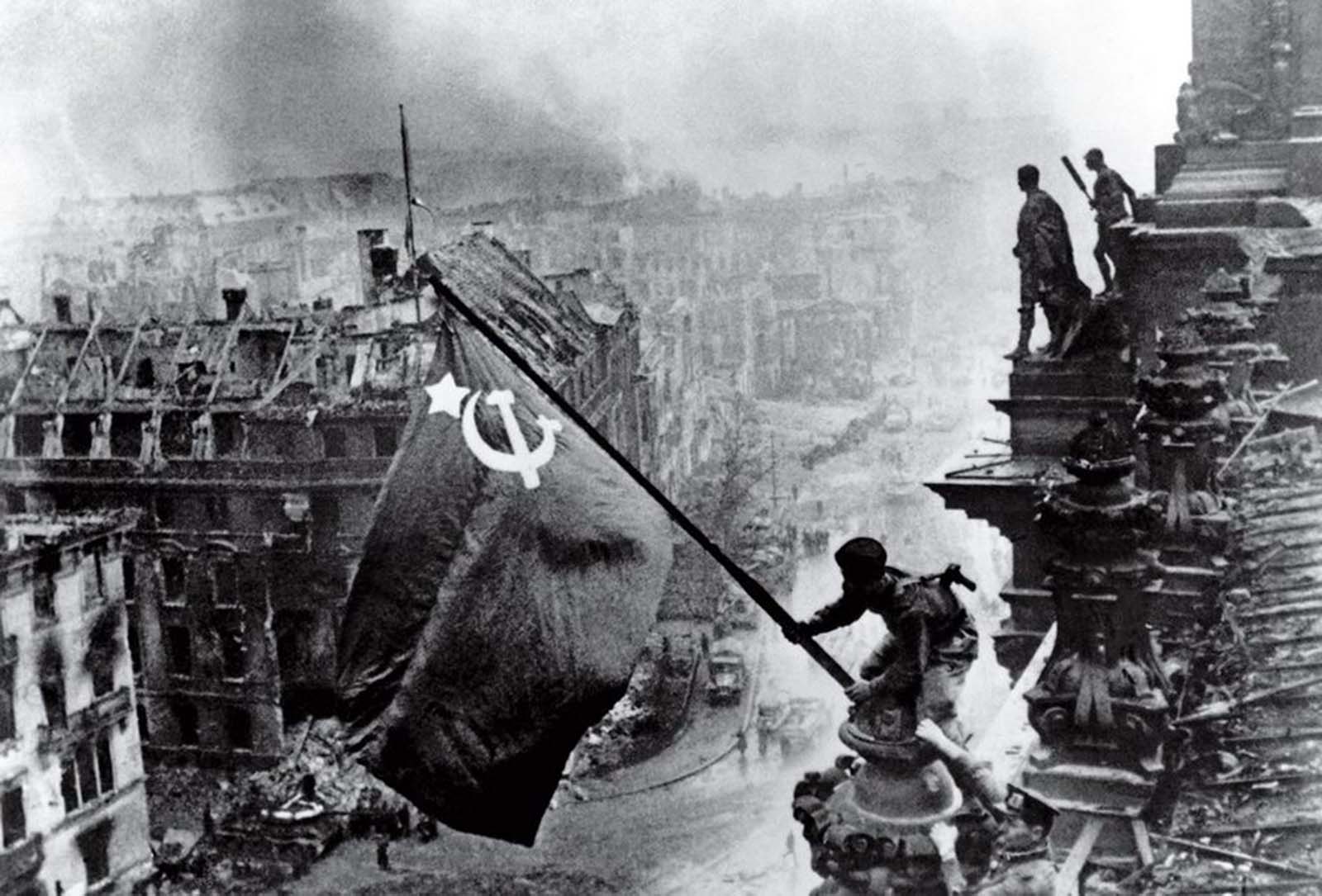 Fotó: Jevgenyij Haldej: Raising the Banner of Victory, Berlin, 1945. május 2. © Jevgenyij Haldej:<br /><br />A Jevgenyij Haldej zászlót kitűző katonájának fotóját - mely már a Mai Manó Házban is bemutattuk - számtalan legenda övezi, és az is biztos, hogy egy újrajátszott pillanatát láthatjuk történelmünknek.