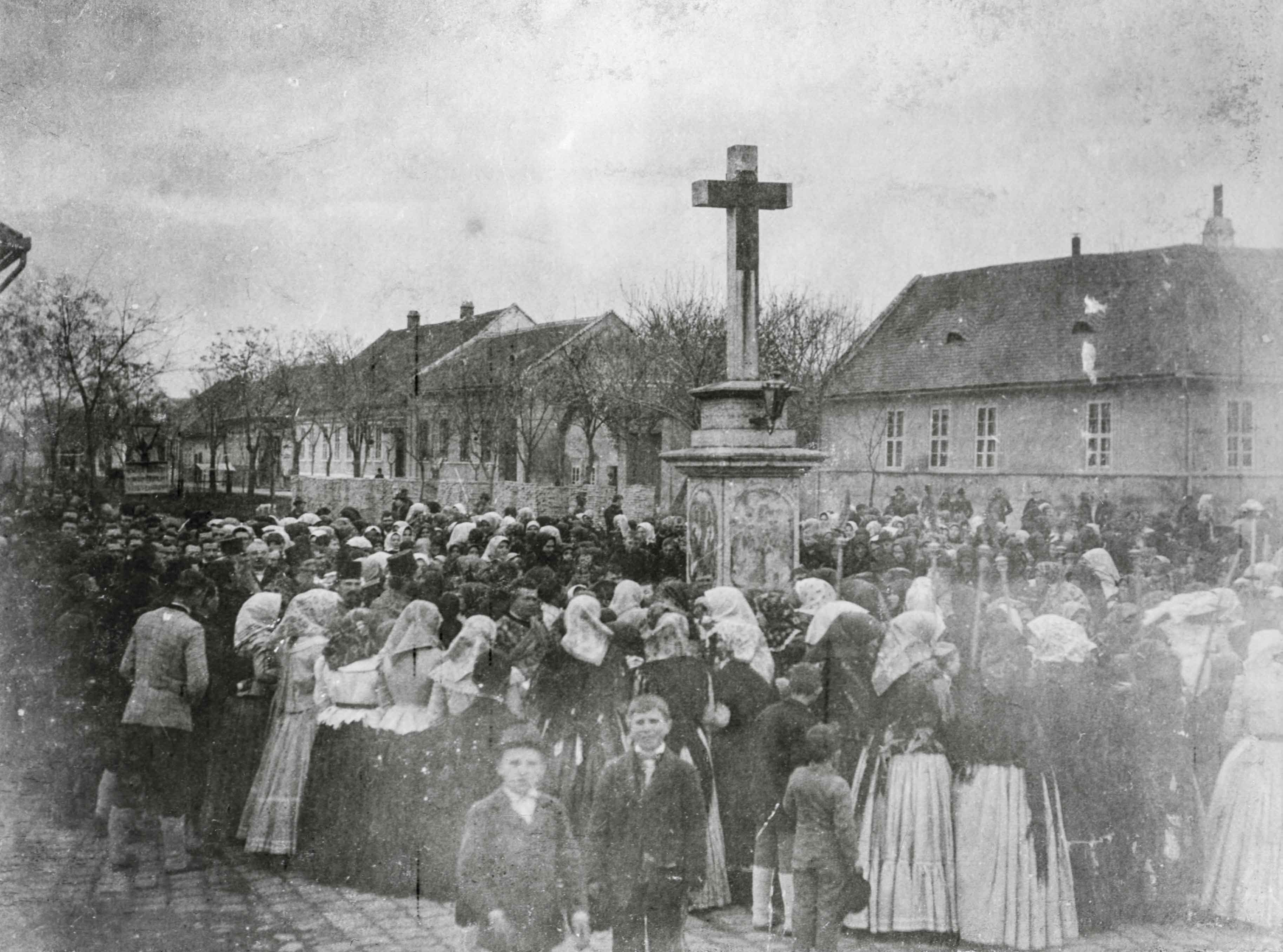 Szerb körmenet. A városfejlődés sajátosságai jól kitapinthatóak Alföldy felvételein. A külső városrészeket földszintes, nádtetős házak sora, falusi utcakép jellemzi, mezítláb táncoló, játszó gyerekekkel, míg a belvárosban az Úrnapi, vagy húsvéti körmenet már néhol emeletes polgárházak között halad el.<br />Zombor, 1907 előtt, F 8493<br /><br />Fotó: Alföldy Flóra © Néprajzi Múzeum