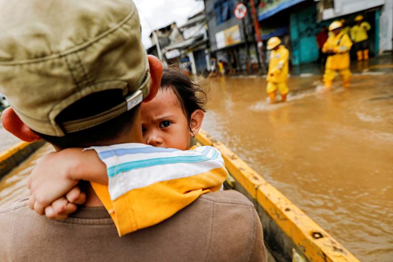 Fotó: Egy apa, kislányát kezében tartva az árvizek sújtotta Jatinegara térségében az esőzések után az indonéziai Jakartában, 2020. január 2-án. REUTERS / Willy Kurniawan