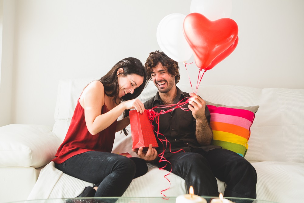young-girl-looking-red-bag-while-her-boyfriend-holds-red-white-balloons.jpg