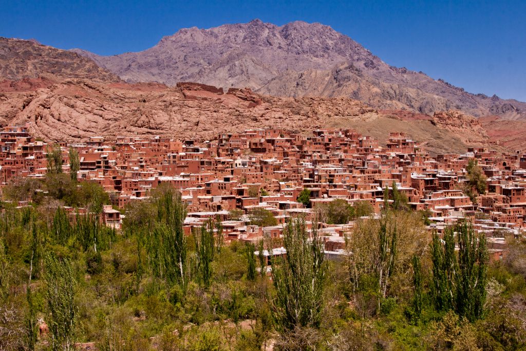 A Zagrosz-hegység vonulatai között, a 3899 méter magas Karkass-hegy északi lejtőjén bújik meg az alig 250 lelket számláló Abyaneh, mely Irán egyik legősibb, több mint 2000 éves települése. A lakosok átlagéletkora pedig erősen 70 év felett van, a fiatalok ugyanis lehetőségek híján elvándoroltak a nagyobb városokba. A 2235 méteres magasságban, a Barzrud-folyó mentén fekvő falu a természettel teljes harmóniában lévő építészet egyik ékköve. Egyedi vörös árnyalatú vályogtéglás épületei számos turistát vonzzanak ide mind Iránból, mind külföldről. 