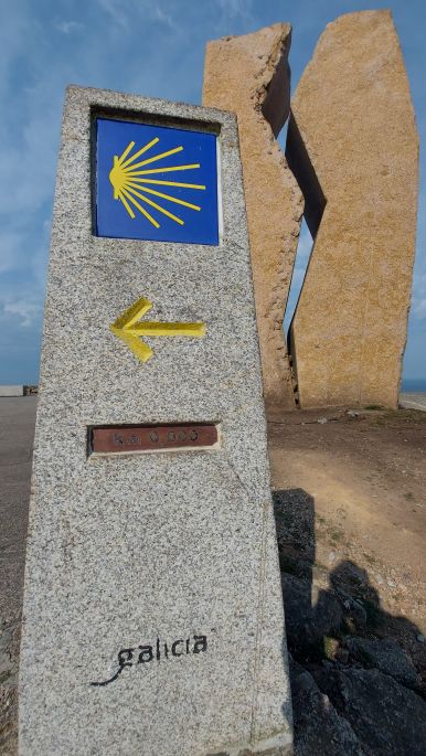 Muxía, a nullás kilométerkő, háttérben az olajkatasztrófa emlékműve