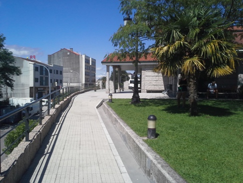 Az alberguét körülvevő betonfal mentén kerítés és járda. 