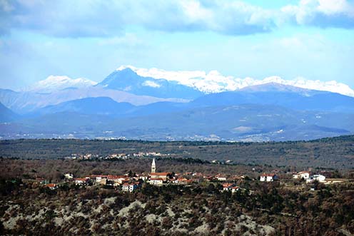Sela na Krasu napjainkban a Hermadáról, mögötte a Komeni-fennsík egy részével, a távolban a Görzi-medencével és a háttérben északnyugat felé egészen a Júliai-Alpok nyúlványaival