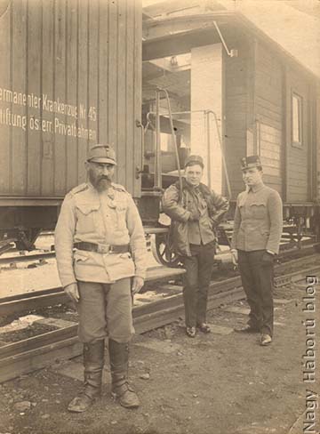 A cs. és kir. 45. sz. állandó kórházvonaton szolgáló egyik idős népfelkelő és a háttérben a kórházvonat tisztjei (balról jobbra): Parányi ezredorvos, vonatparancsnok, mellette Kósa György