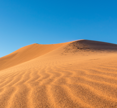 closeup-sand-ripples-sand-dunes-desert-against-clear-blue-sky.png