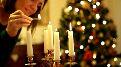 stock-footage-young-woman-lighting-a-candle-christmas-tree-in-background.jpg