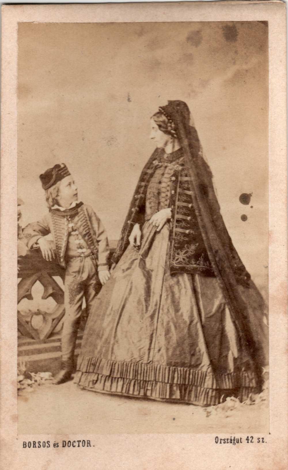 Borsos és Doctor: Magyaros ruhát viselő női és egy kisfiú álló műtermi portréja, korlát mellett – Magángyűjtemény