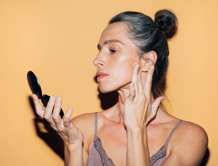 woman-looking-at-her-face-in-a-mirror-715x545.jpg