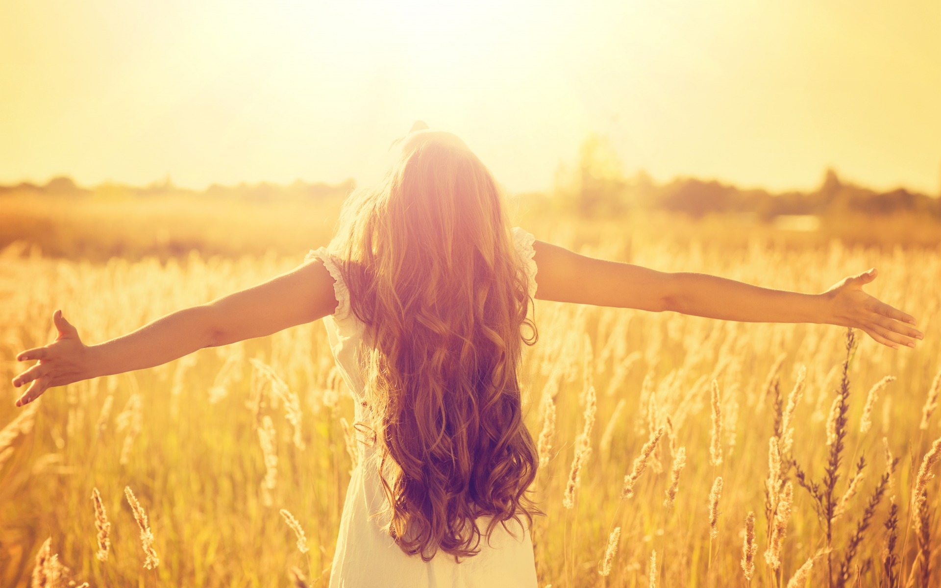 a-beautiful-girl-with-very-curl-long-hair-standing-on-the-wheat-field-in-sunshine-her-outstretched-arms-enjoys-the-freedom.jpg