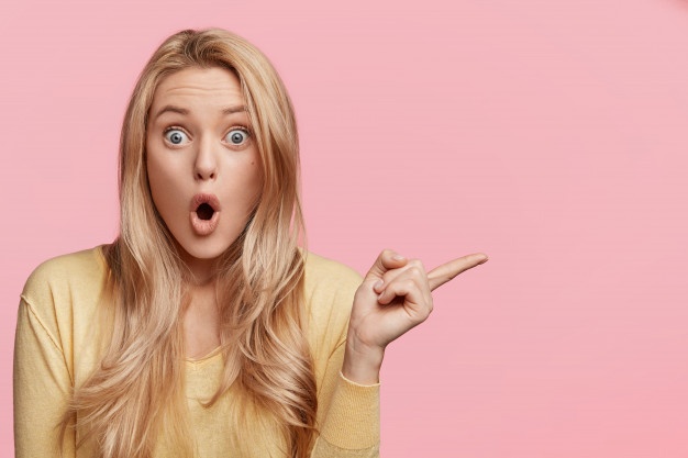 terrifed-young-woman-warns-you-about-something-indicates-aside-with-fore-finger-keeps-mouth-widely-opened-stares-with-bugged-eyes-isolated-pink-wall-advertising-concept_273609-2957.jpg