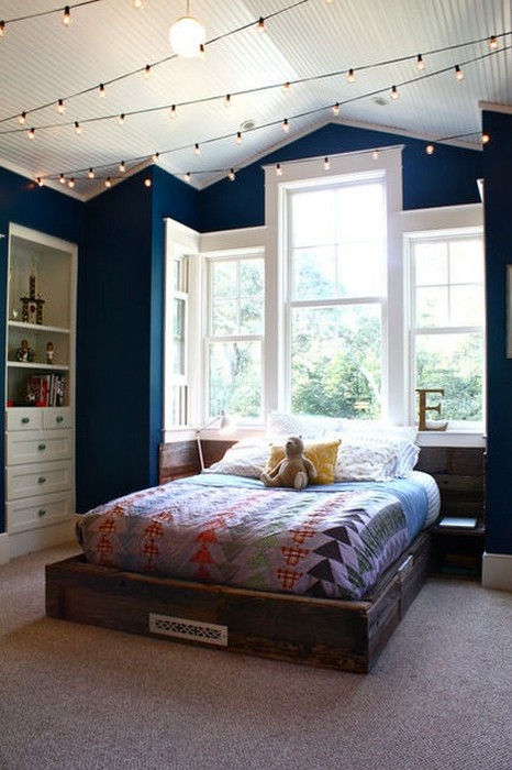 dark-blue-walls-trimmed-in-white-twinkle-lights-on-the-ceiling-recessed-wall-shelves-stunning-picture-window-instead-of-headboard-i-love-this-space.jpg
