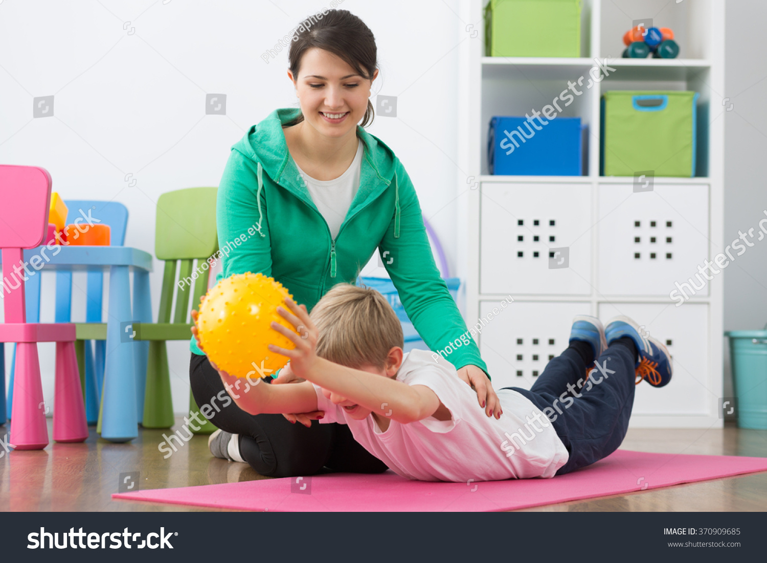 stock-photo-boy-exercising-with-small-gym-ball-and-his-smiling-instructor-370909685.jpg