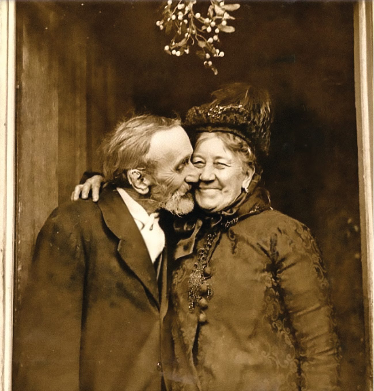 Meghitt karácsonyi fotó az 1880-as évekből: idős pár a fagyöngy alatt. Az asszony szélesen mosolyog, de a fogait nem mutatja. (Public Domain)