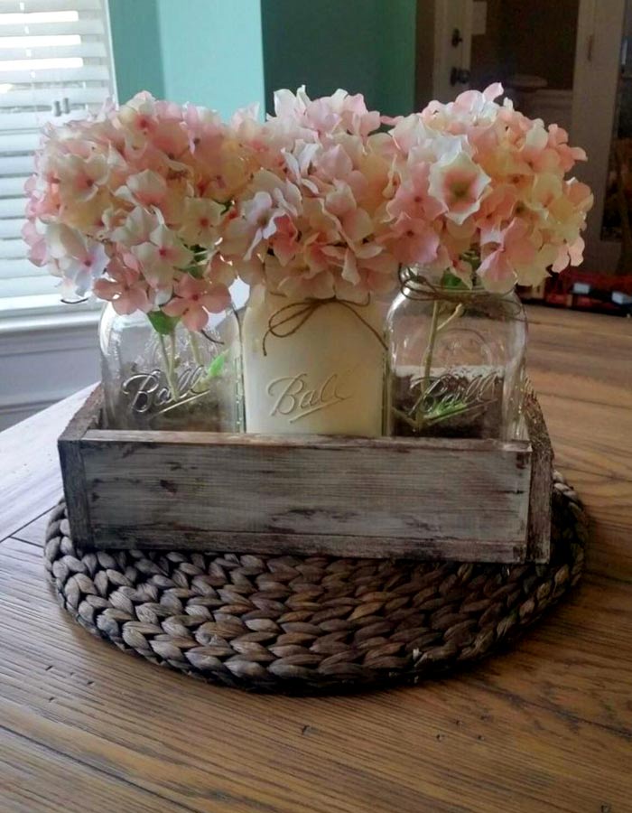 Néhány szép befőttesüveg, egy antikolt láda és pár gyönyörű virág, és már kész is a DIY-asztaldísz.