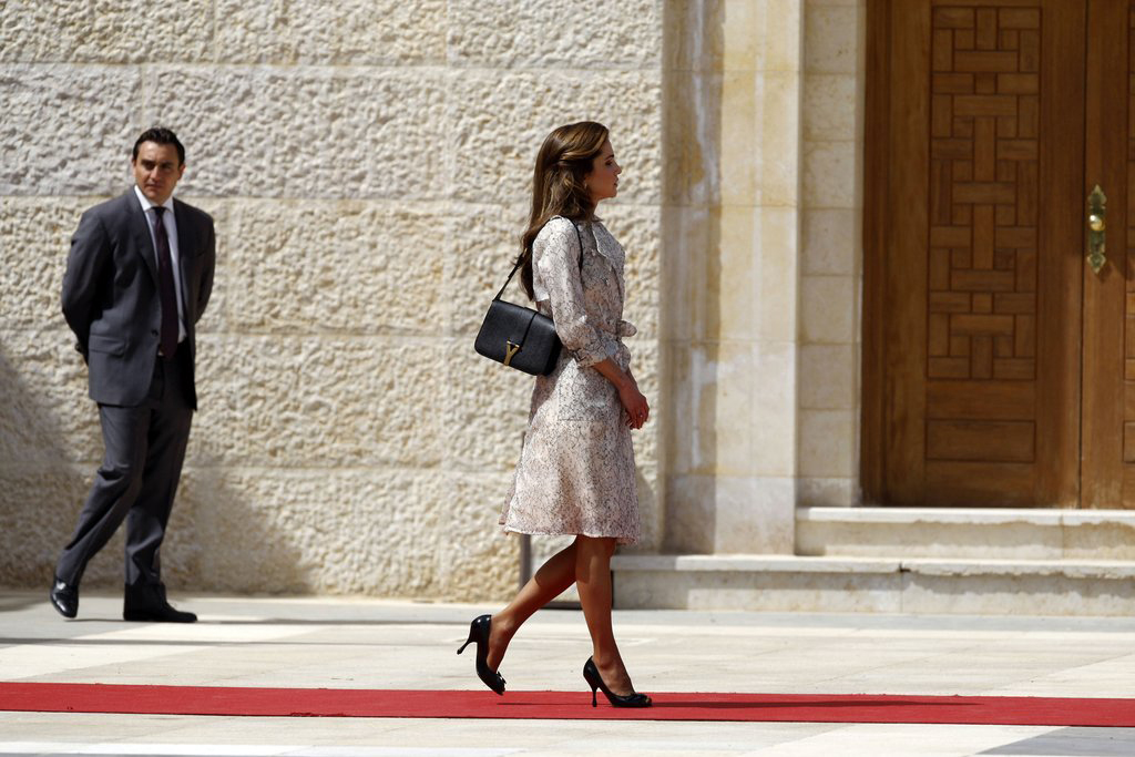 Egy elegáns Yves Saint Laurent tervezésű táska lóg a királyné karja alatt.