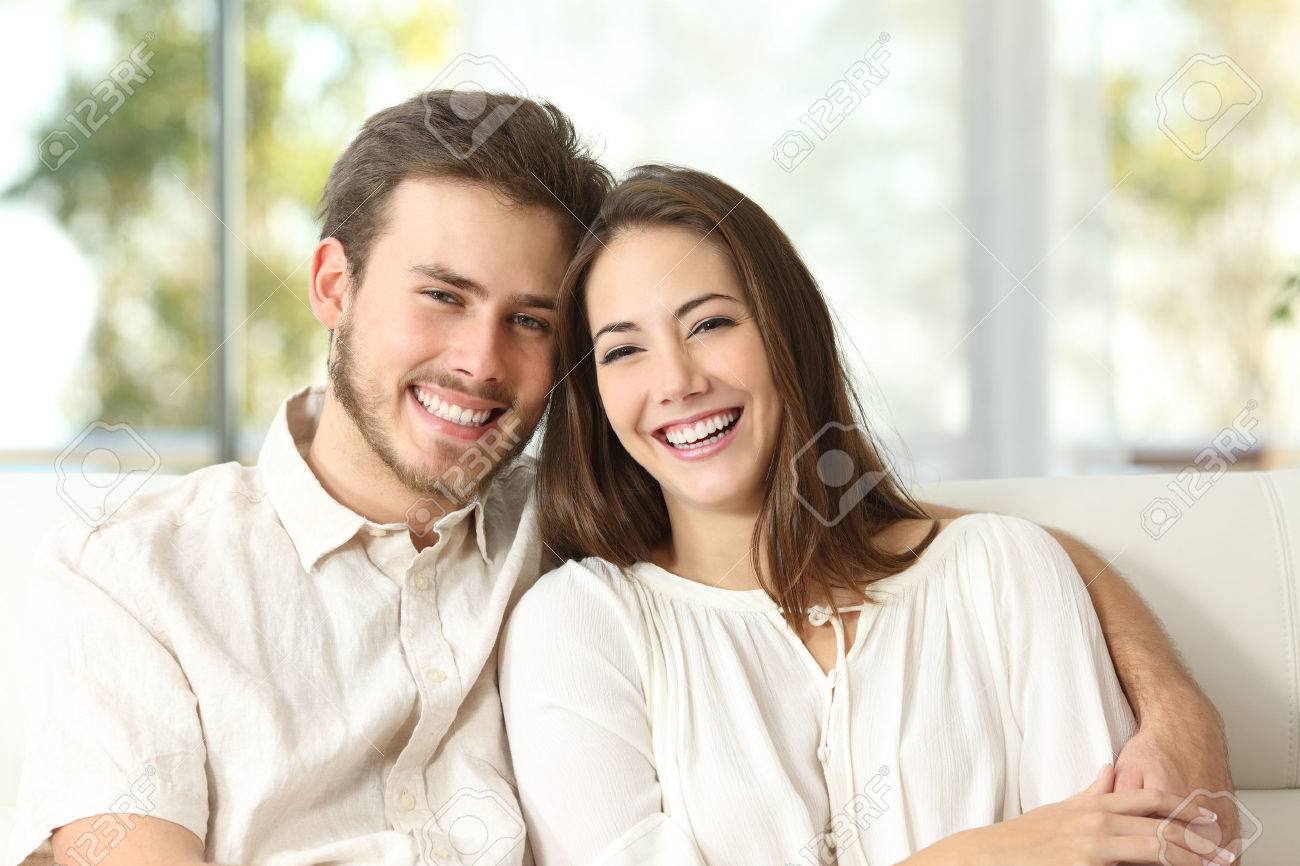 52407680-happy-couple-sitting-on-a-couch-at-home-and-looking-at-camera.jpg