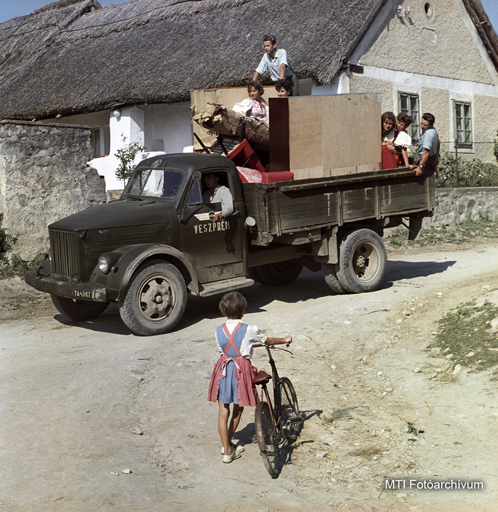 1962. szeptember 13. Zánka. A veszprémi TEFU teherautója áll - platóján a kultúrházba szállítandó bútorokkal - a Kossuth utcai Geiszler-ház előtt, ahol a művelődési házba tartó néptáncosok is felszálltak a járműre. MTI Fotó: Fehérváry Ferenc