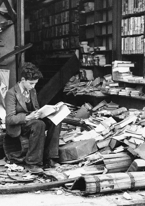 1940. London. Egy fiatalember a lebombázott könyvesbolt romjai közt olvas..jpg