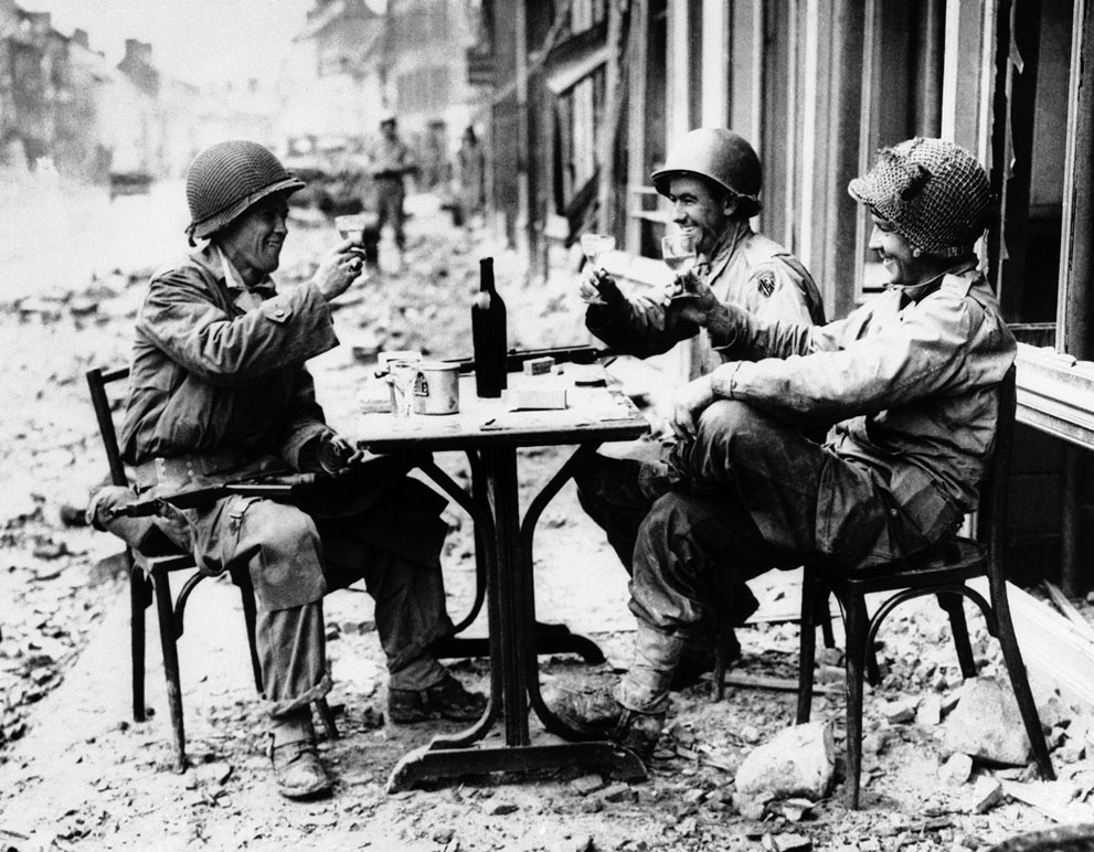 1944. Három amerikai katona iszik, egy ostrom után elfoglalt francia városka kocsmája előtt..jpg