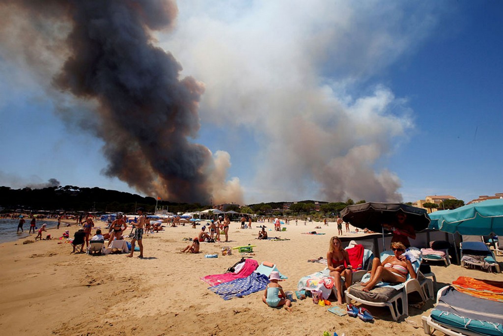 2017_07_26_smoke_fills_the_sky_above_a_burning_hillside_as_tourists_relax_on_the_beach_in_bormes-les-mimosas_france.jpg
